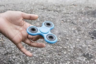 Cropped hand holding fidget spinner on road