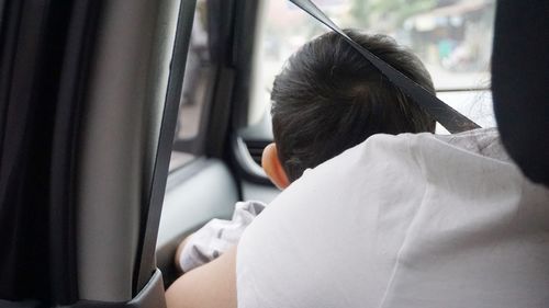 Rear view of woman sitting with baby in car