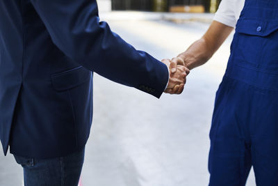 Close-up of businessman and worker shaking hands in a factory