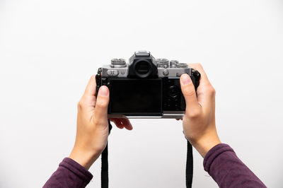 Cropped hand holding camera against white background