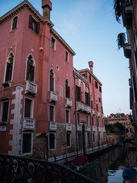 Canal amidst buildings in city against sky