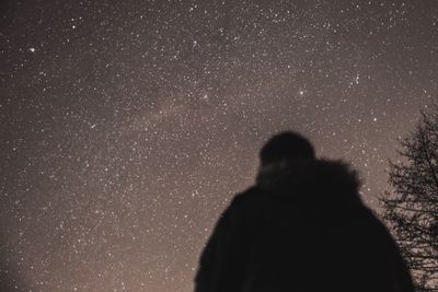 Rear view of silhouette man standing against star field at night