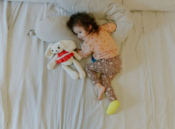 A baby girl with a cast on her leg lies on the bed.