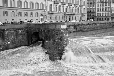 Water flowing on dam in sea against buildings