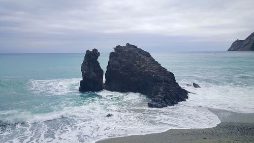 Rock formation on beach against sky