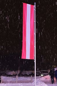 Red flag on snow covered tree at night