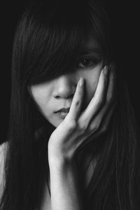 Portrait of young woman against black background