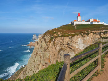 Lighthouse by sea against sky