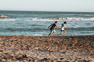 Men playing at beach against sky