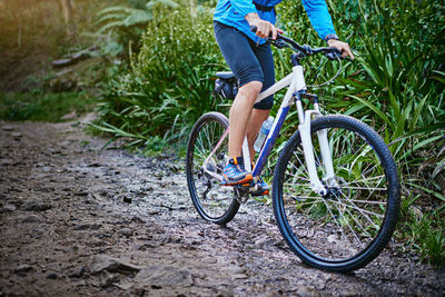 Low section of man riding bicycle on field