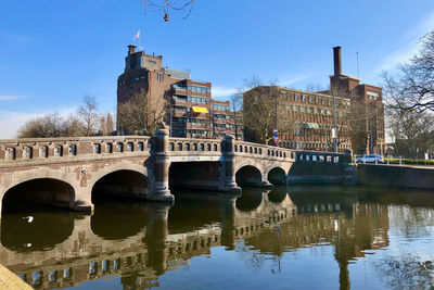 Arch bridge over river against buildings