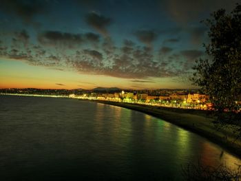 Bridge over river in city against sky during sunset