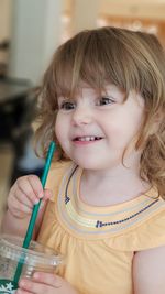 Portrait of cute girl holding camera at home