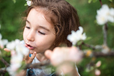 Close-up of young woman blowing flowers