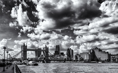 Tower bridge and cityscape against cloudy sky