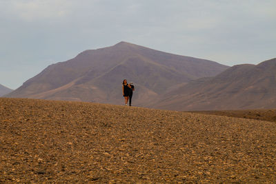 Rear view of man standing on desert against sky