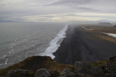 View to endless ocean black volcanic sand beach from dyrholaey cape viewpoint, vik, south iceland.