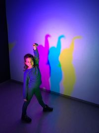 Full length of woman standing against illuminated wall