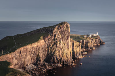 High angle view of cliff by sea against sky during sunset