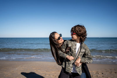 Friends enjoying at beach against sky