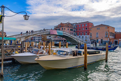 Boats moored at harbor against buildings in city