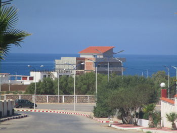 Buildings by sea against blue sky