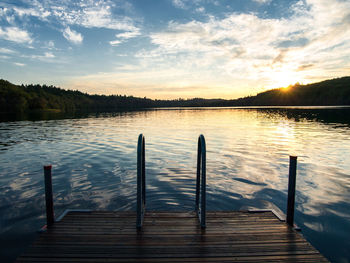Pier on lake against sky during sunset