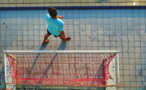 Directly above shot of man walking on footpath by sports net