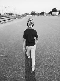 Rear view of boy standing on road in city