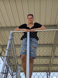 Low angle portrait of young woman standing by railing