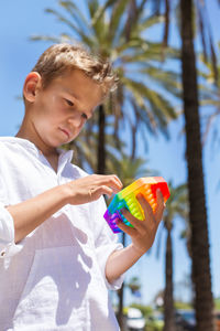 Boy holding toy while standing outdoors