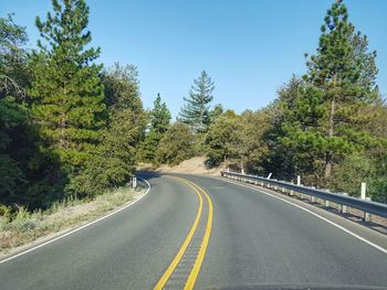 Road amidst trees against clear sky