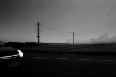 Car on road amidst field against sky