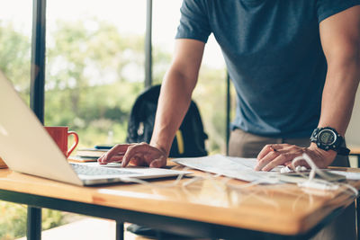 Midsection of man using laptop on table