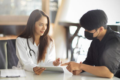 Doctor examining patient wearing mask at clinic