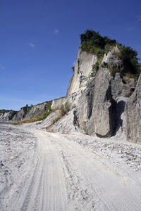 Dirt road amidst rocky mountains against sky