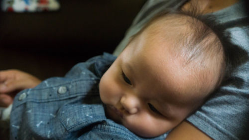 Close-up of baby boy relaxing in mother arm