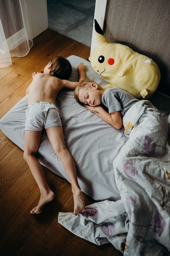 HIGH ANGLE VIEW OF BOY LYING ON BED AT HOME