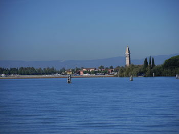 Scenic view of sea by buildings against clear blue sky