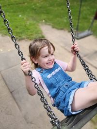 Smiling cute girl swinging in playground