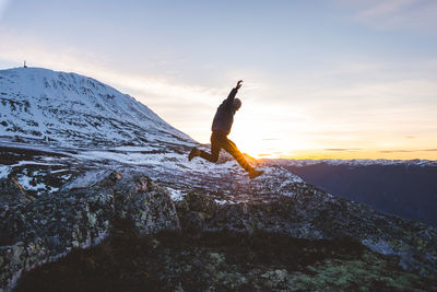 Rear view of woman standing on mountain against sky during sunset