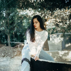 Young woman standing against trees