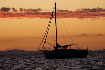 Silhouette sailboat on sea against sky during sunset