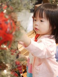 Portrait of cute girl standing by christmas tree