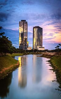 Reflection of buildings in lake against sky during sunset