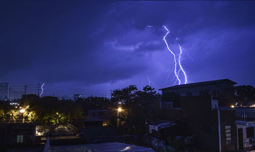 Lightning over illuminated buildings in city at night