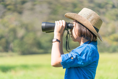 Side view of teenage girl looking through binoculars