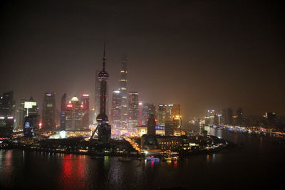 Tall buildings and communication tower in city with river and boats in foreground