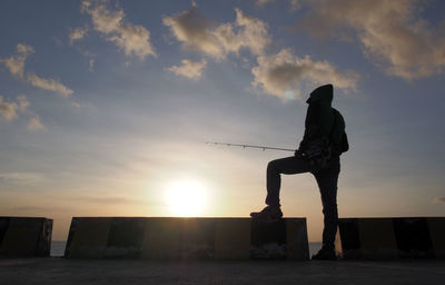 Silhouette man standing against sky during sunset