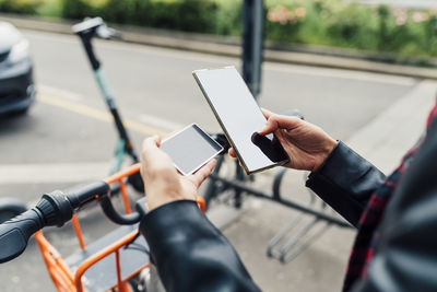 Woman with credit card using smart phone at bicycle parking station